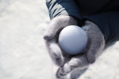 Photo of Woman holding snowball outdoors on winter day, closeup. Space for text
