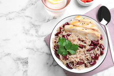 Photo of Delicious rice with beans and meat served on white marble table, flat lay. Space for text