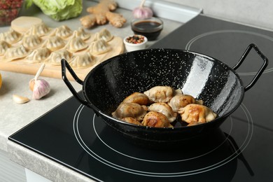 Photo of Cooking gyoza on frying pan with hot oil in kitchen