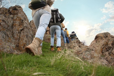 Group of hikers with backpacks climbing up mountains, closeup