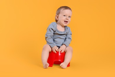 Little child sitting on baby potty against yellow background