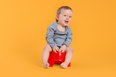 Photo of Little child sitting on baby potty against yellow background