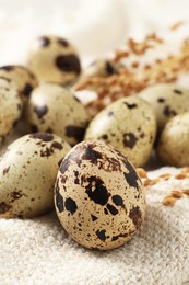 Photo of Fresh quail eggs on white burlap fabric, closeup