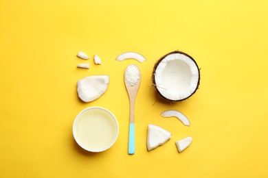 Photo of Bowl of natural organic oil and coconut on yellow background, flat lay