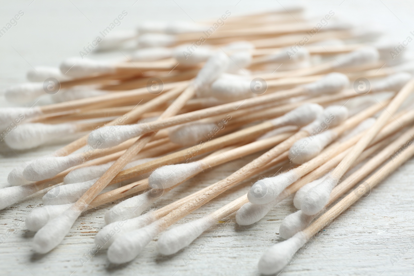 Photo of Pile of cotton swabs on white wooden background, closeup