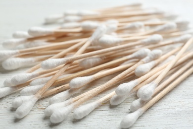 Photo of Pile of cotton swabs on white wooden background, closeup