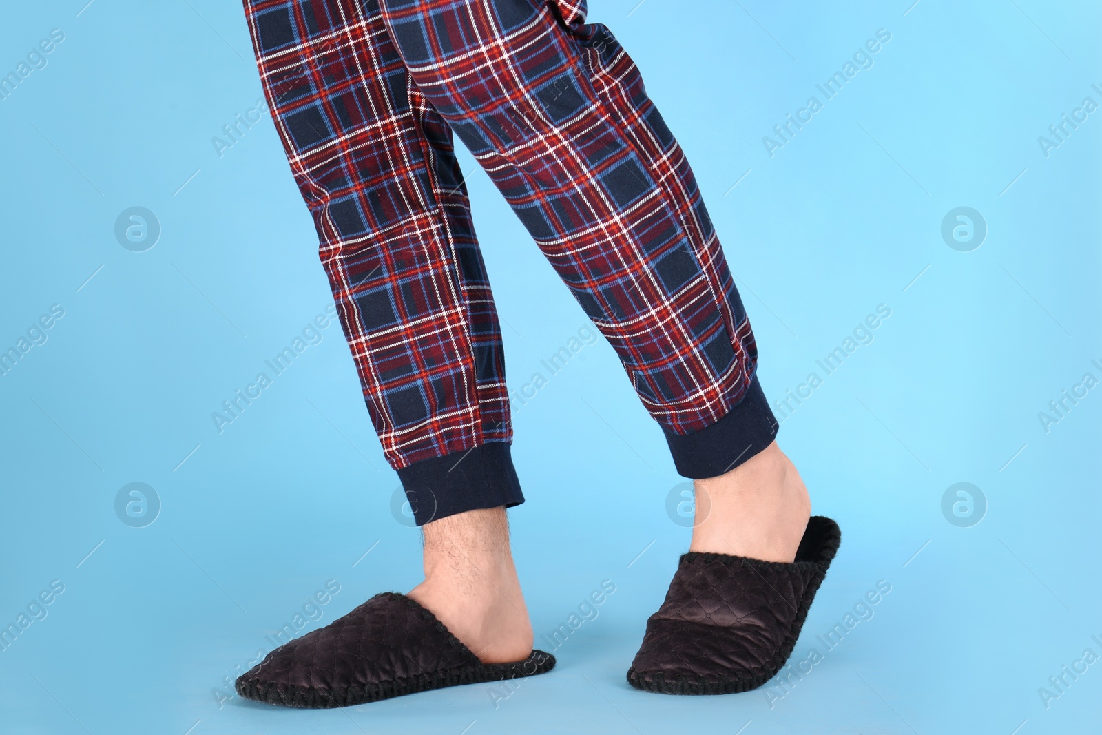 Photo of Man in warm soft slippers on light blue background, closeup