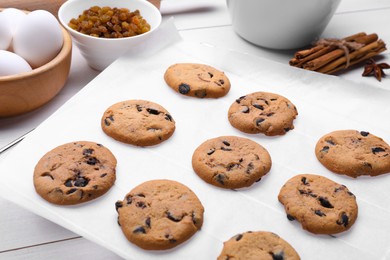 Photo of Parchment baking paper with tasty cookies on white table, closeup