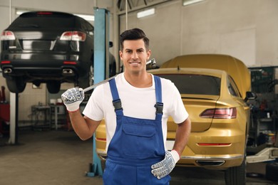 Portrait of professional mechanic with tire wrench at automobile repair shop
