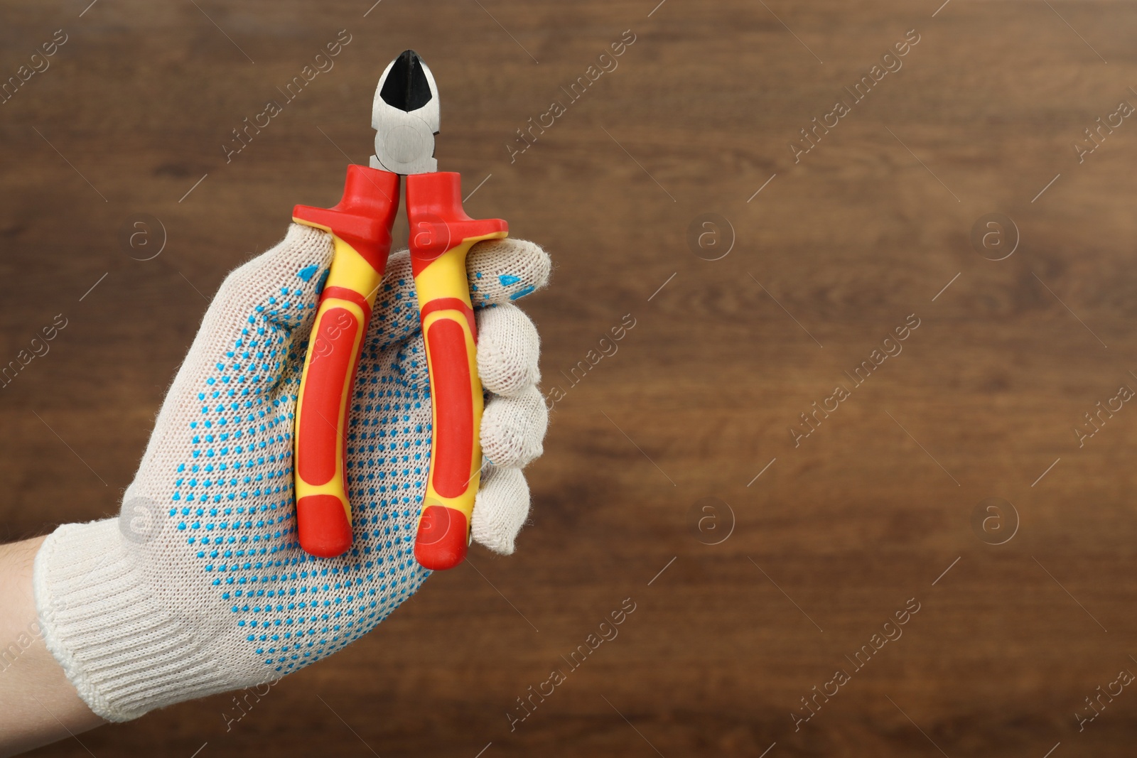 Photo of Man with diagonal pliers on wooden background, closeup. Space for text