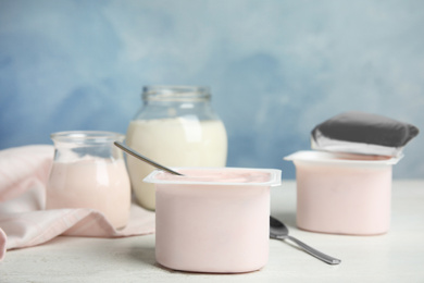 Photo of Tasty organic yogurt on white wooden table against light blue background. Space for text