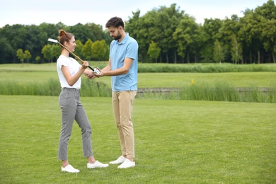 Coach teaching woman to play golf on green course