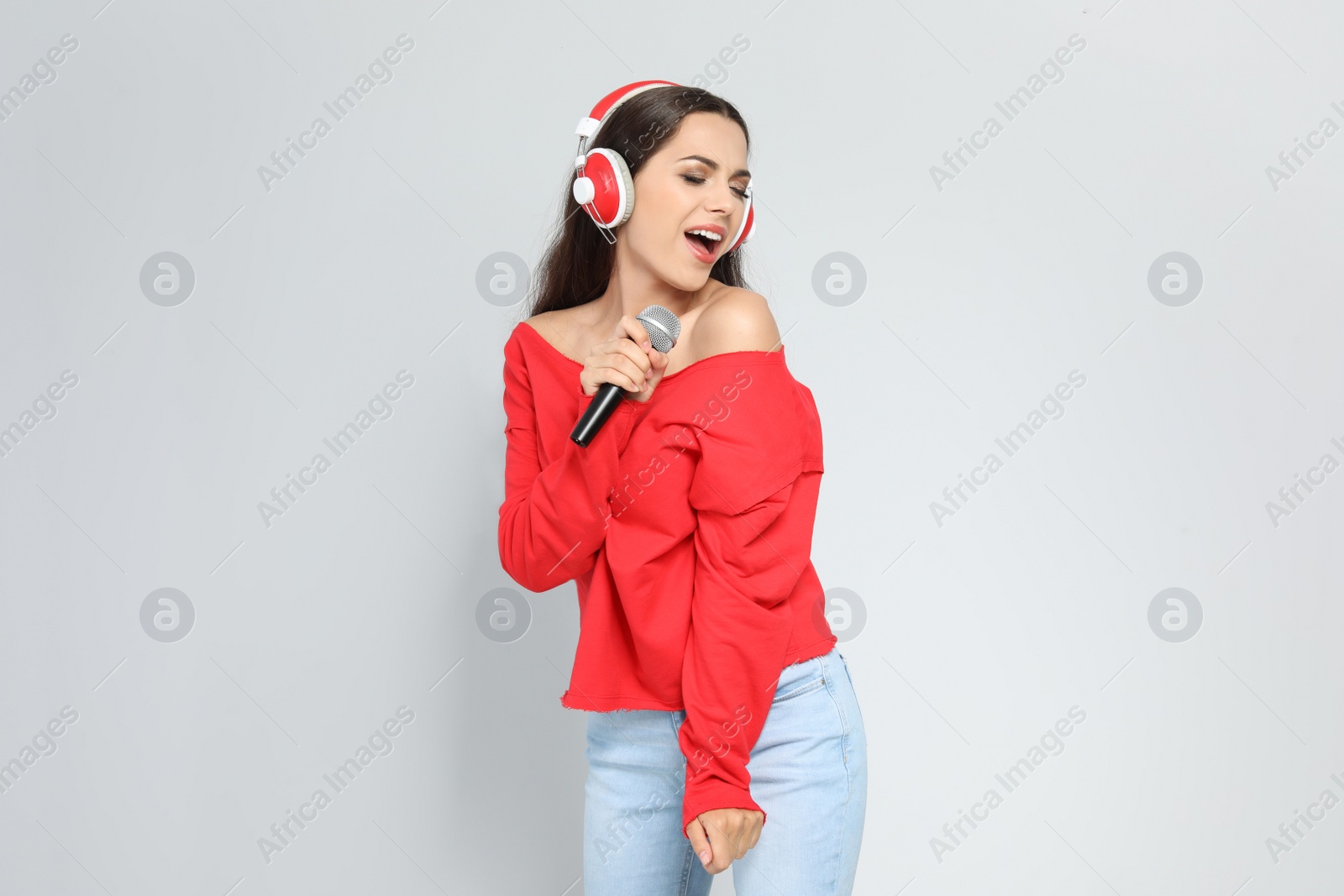 Photo of Young woman singing into microphone on color background. Christmas music