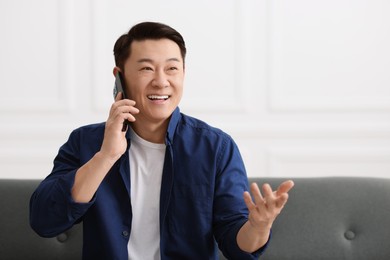 Photo of Portrait of smiling businessman talking by smartphone indoors. Space for text