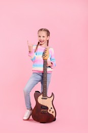 Photo of Cute girl with electric guitar on pink background