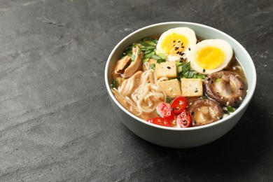 Photo of Noodle soup. Bowl of delicious ramen on black table, closeup. Space for text