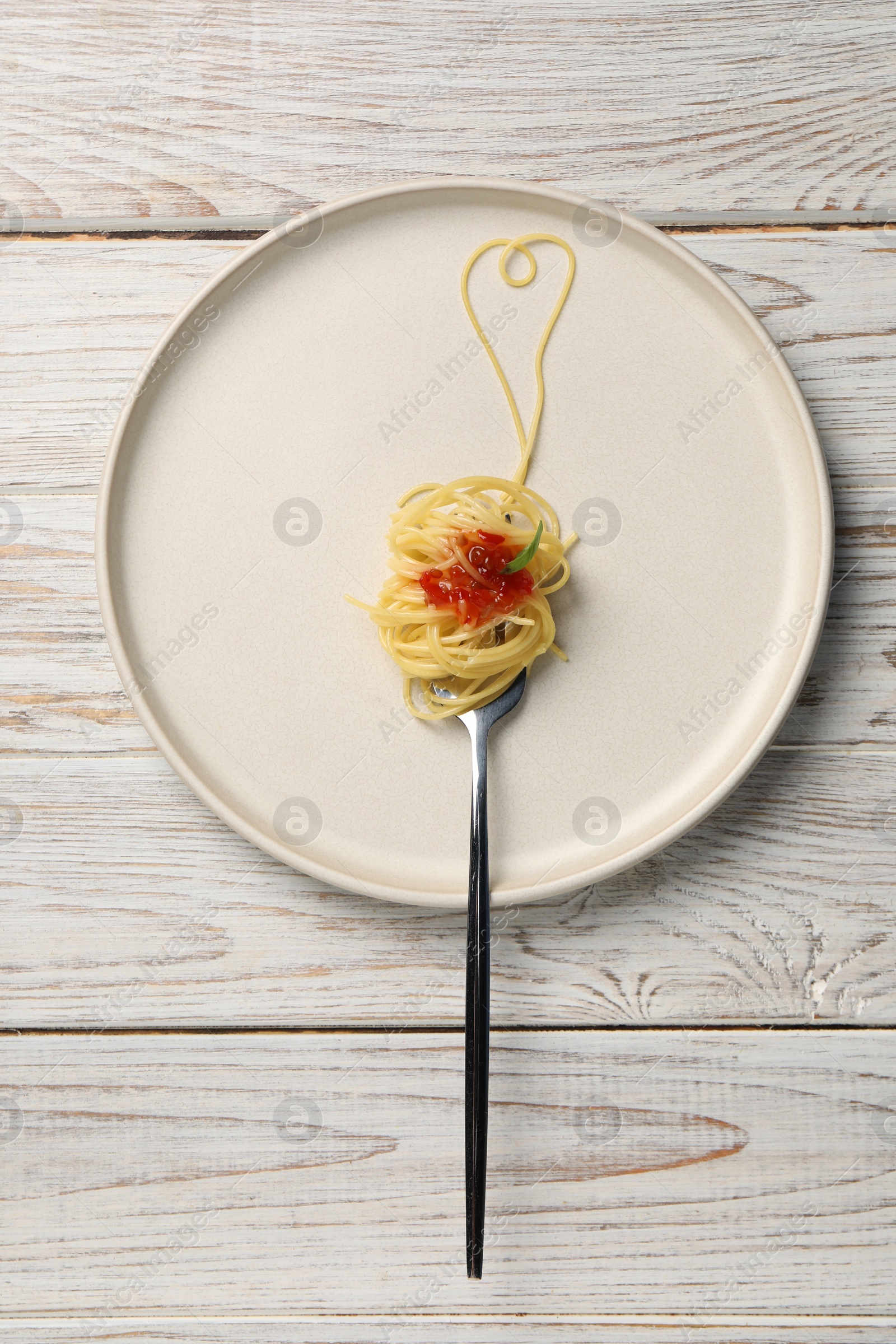 Photo of Heart made with spaghetti and fork on white wooden table