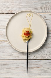 Heart made with spaghetti and fork on white wooden table