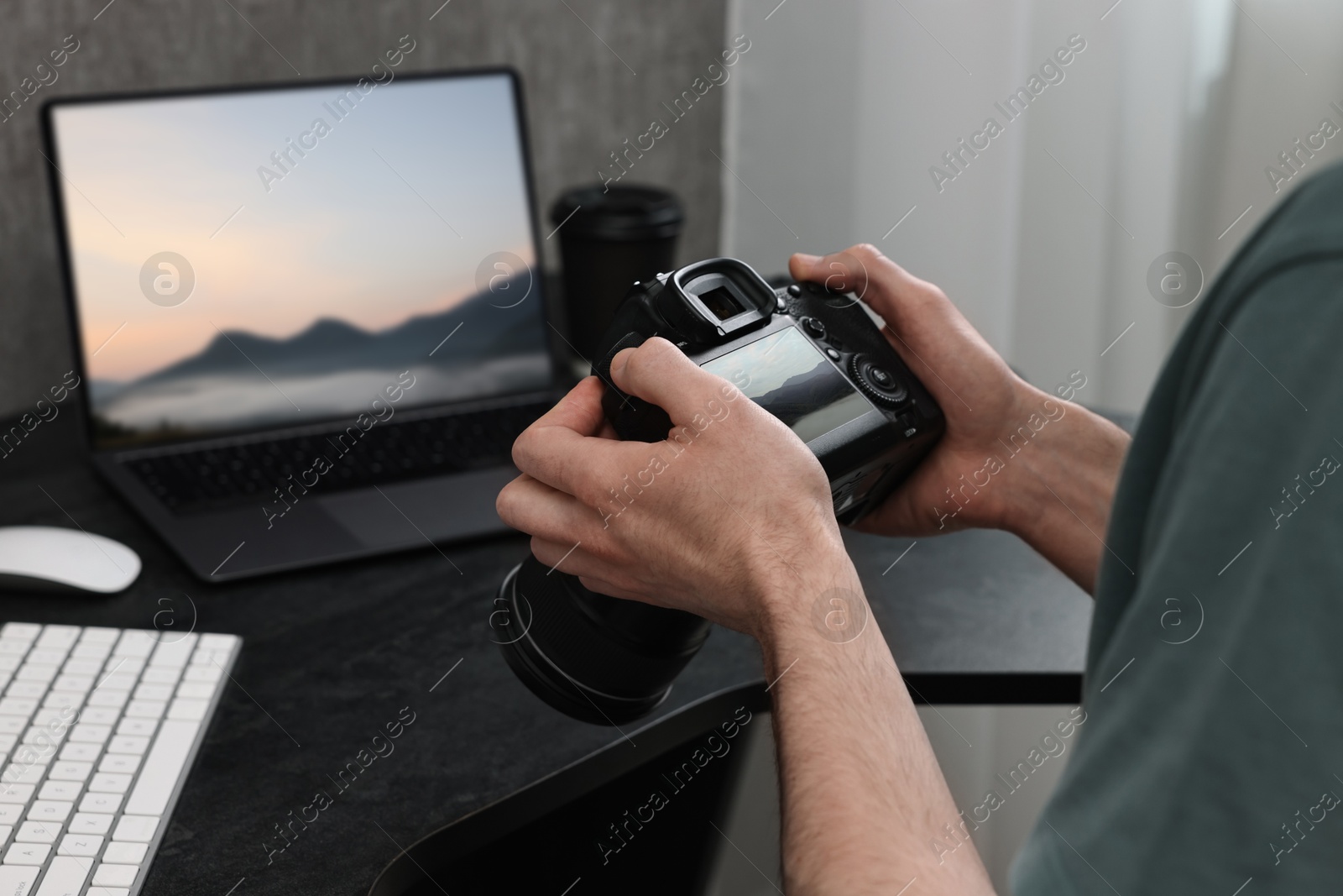 Image of Man with professional photo camera looking at shot of mountain indoors, closeup