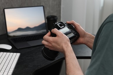 Image of Man with professional photo camera looking at shot of mountain indoors, closeup