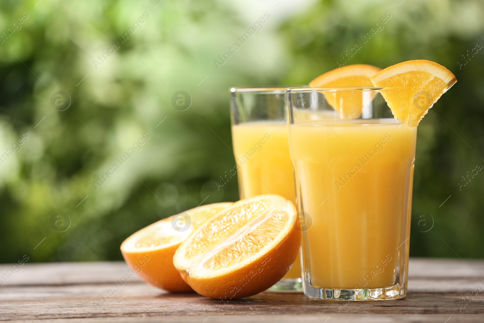 Photo of Glasses of orange juice and fresh fruit on wooden table. Space for text