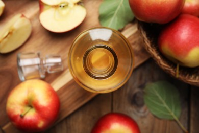 Photo of Natural apple vinegar and fresh fruits on wooden table, flat lay