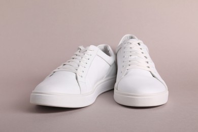 Pair of stylish white sneakers on grey background