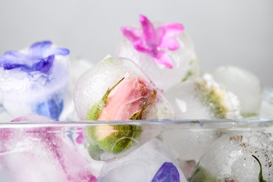 Photo of Glass bowl with floral ice cubes on light background, closeup