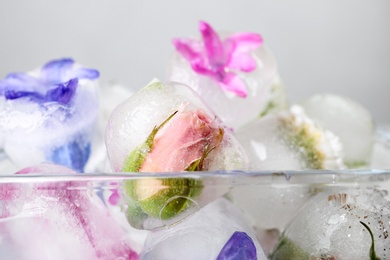 Glass bowl with floral ice cubes on light background, closeup