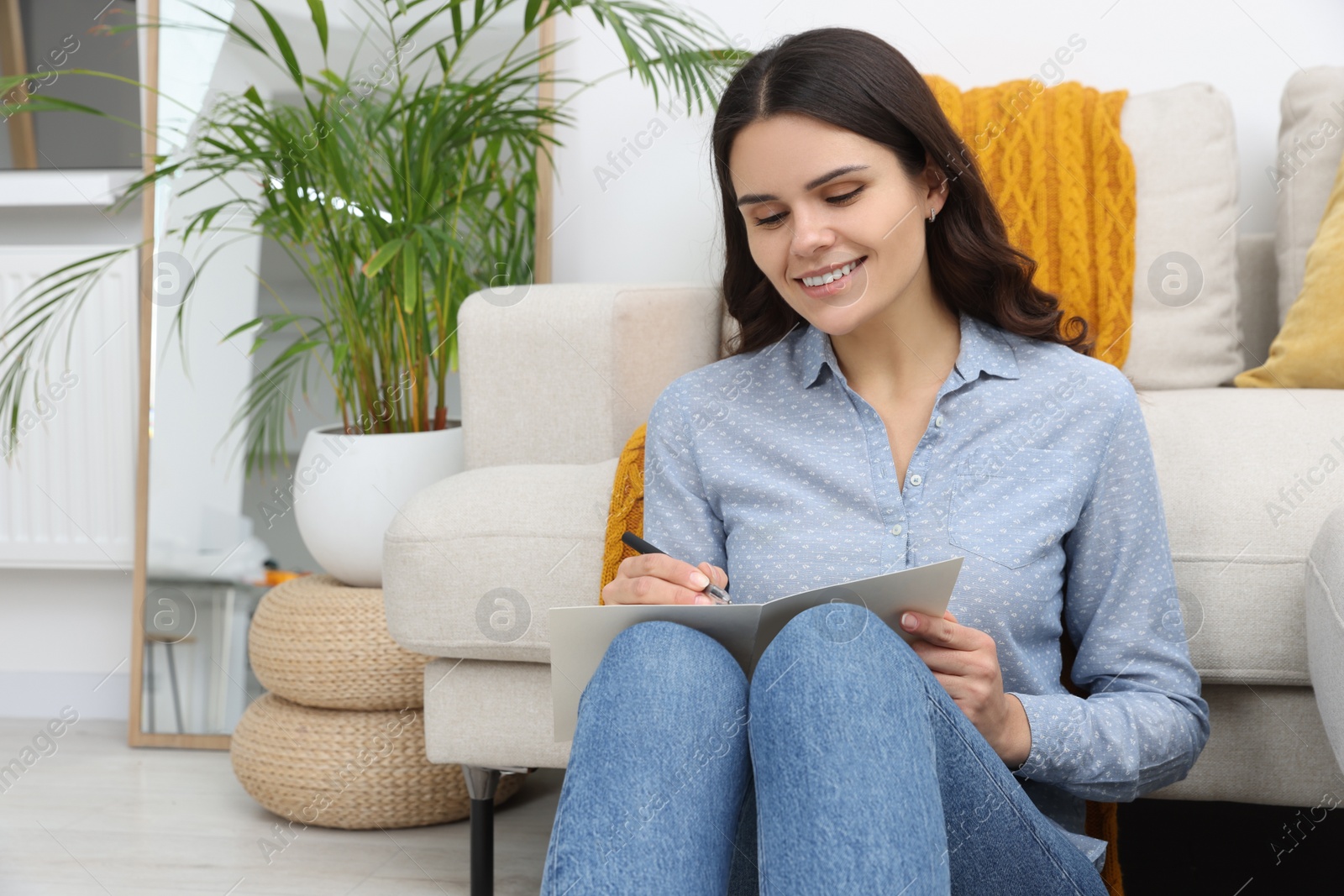 Photo of Young woman writing message in greeting card indoors