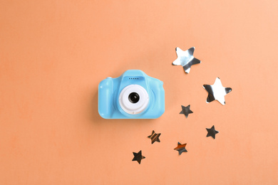 Toy camera and stars on orange background, flat lay