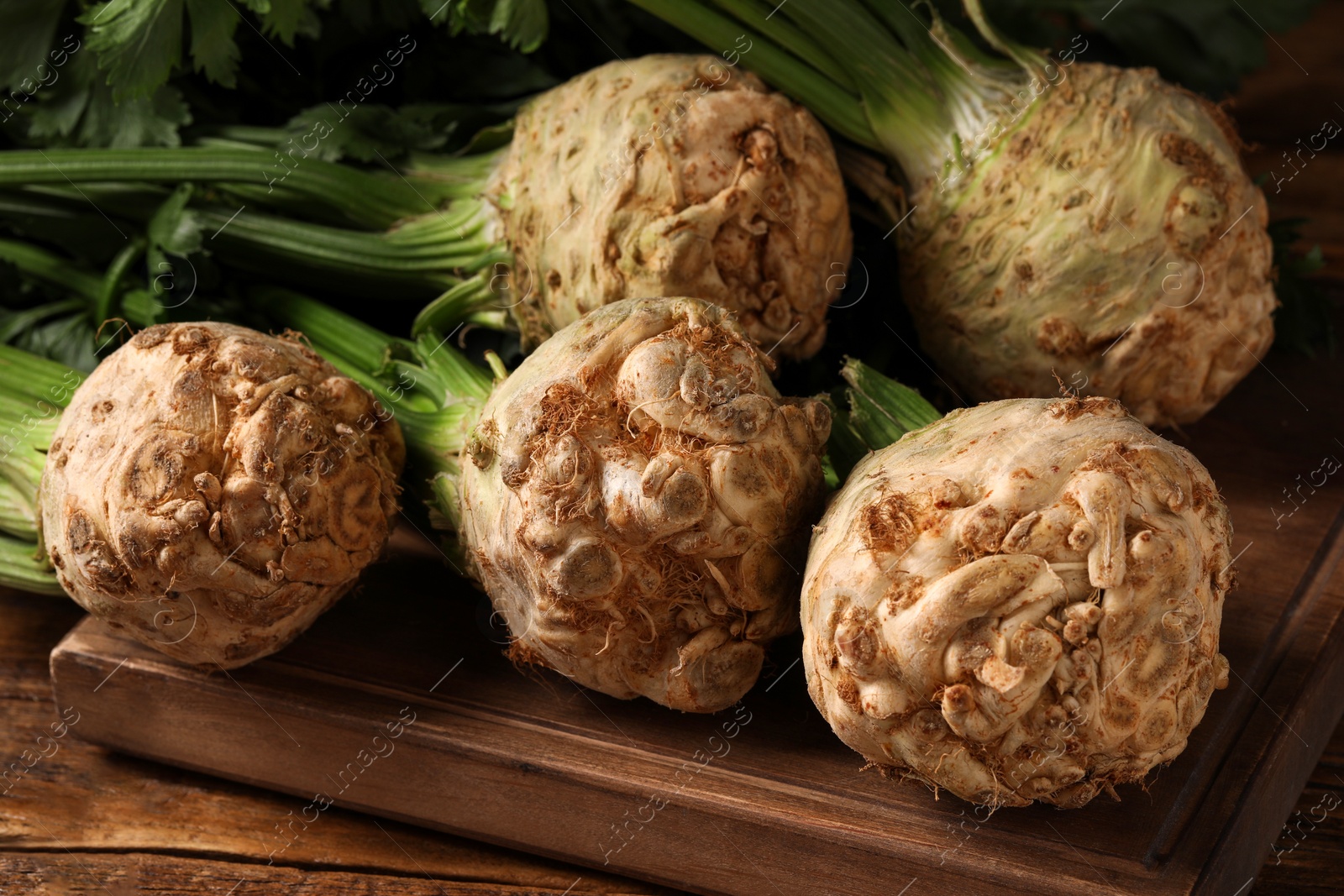 Photo of Fresh raw celery roots on wooden table, closeup