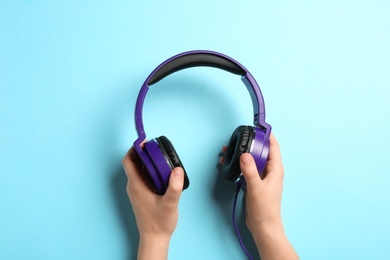 Photo of Woman holding stylish headphones on color background, closeup