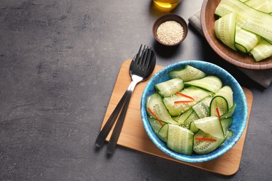 Photo of Flat lay composition with plate of fresh cucumber salad and space for text on table