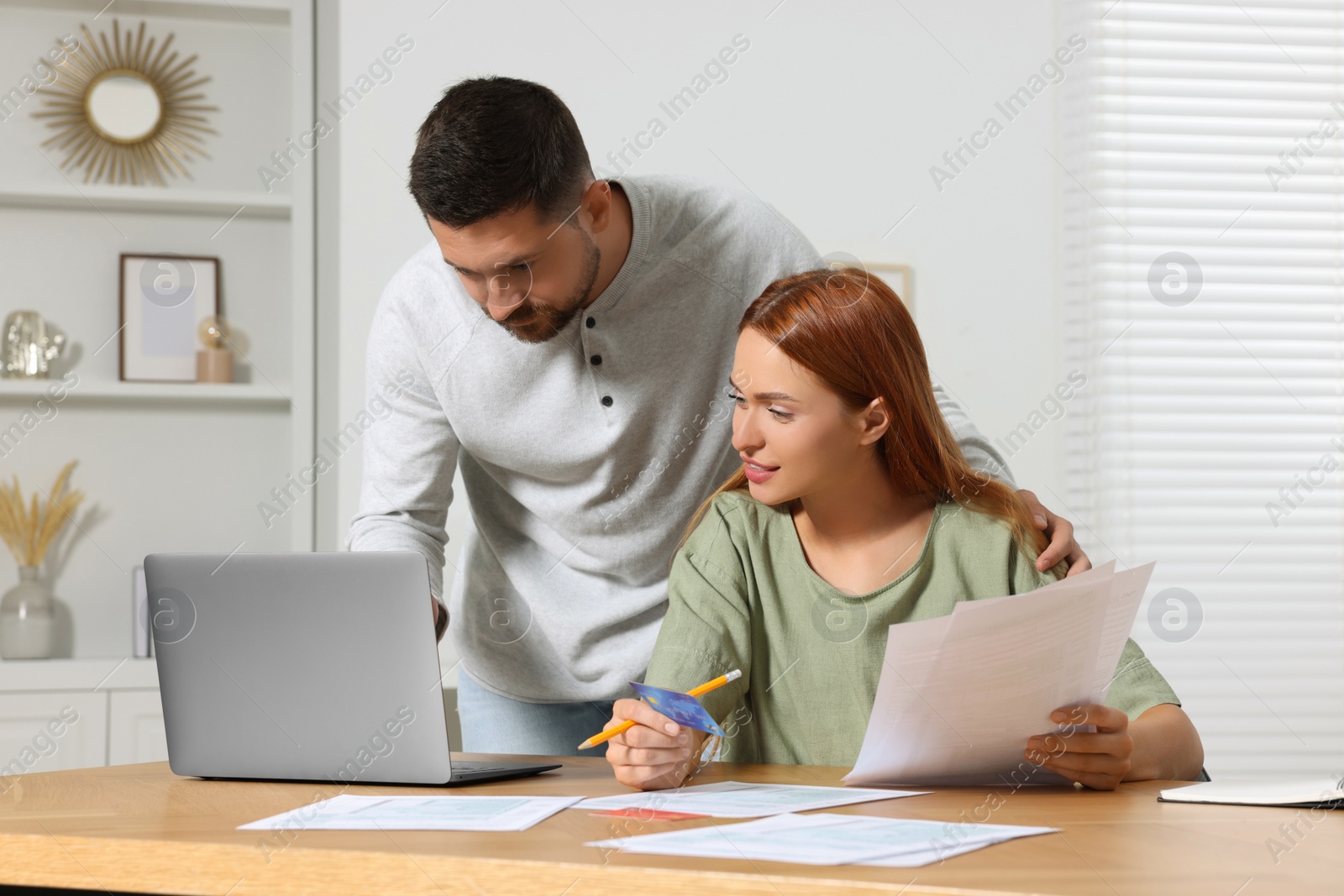 Photo of Couple with credit card using laptop for paying taxes online at home