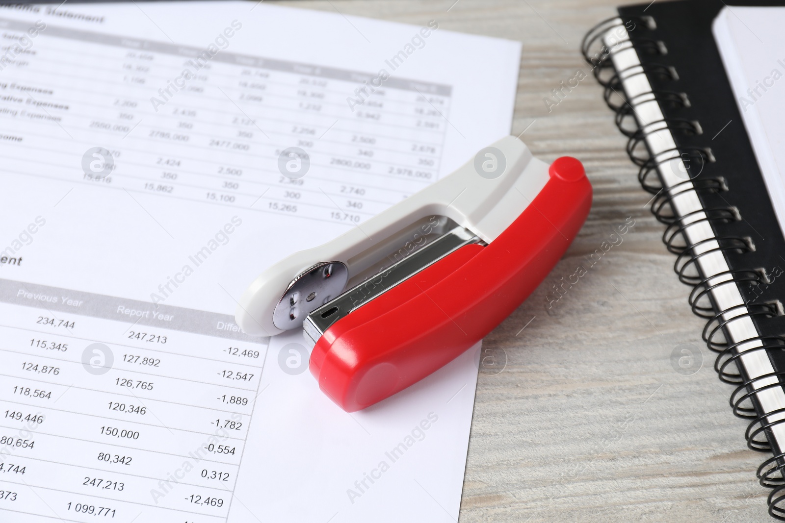 Photo of Stapler, document and notebooks on wooden table