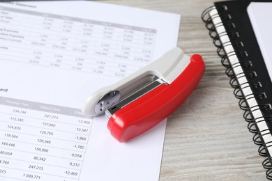 Stapler, document and notebooks on wooden table