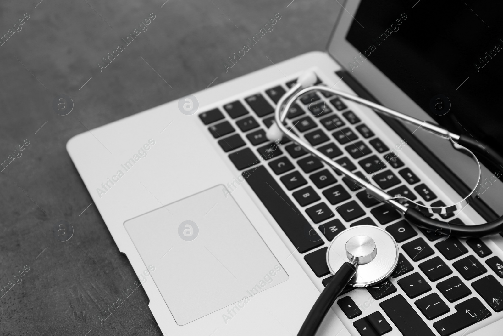 Photo of Modern laptop and stethoscope on table. Technical support concept