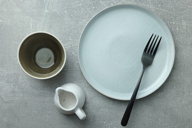 Photo of Stylish empty dishware and fork on light grey table, flat lay