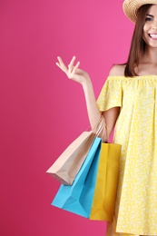 Photo of Young woman with shopping bags on color background