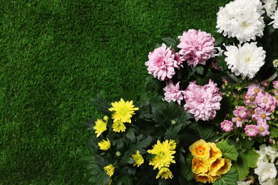 Different beautiful flowers on green grass, flat lay. Space for text