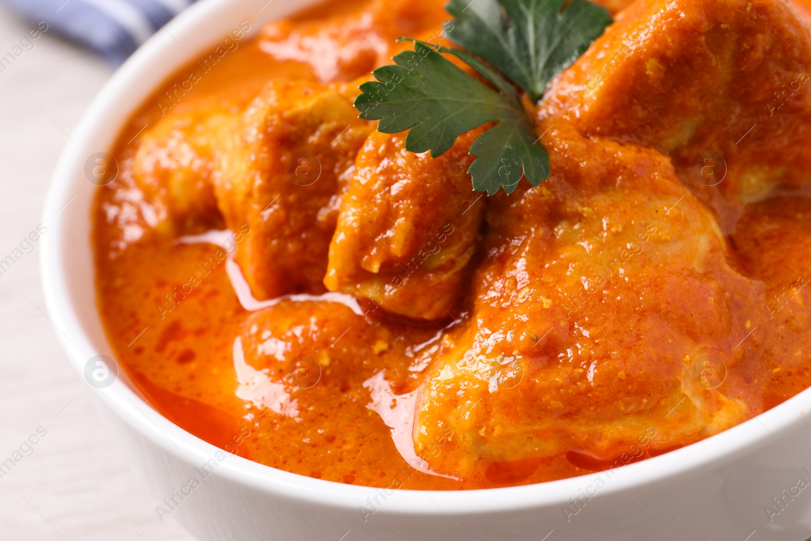 Photo of Bowl of delicious chicken curry on white table, closeup