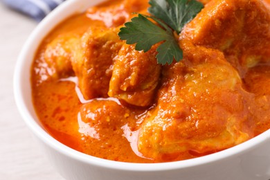 Bowl of delicious chicken curry on white table, closeup