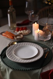 Table setting with burning candles, appetizers and dishware. Christmas celebration