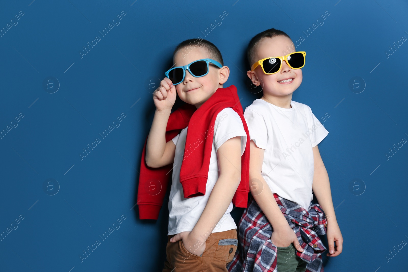 Photo of Portrait of cute twin brothers with sunglasses on color background. Space for text