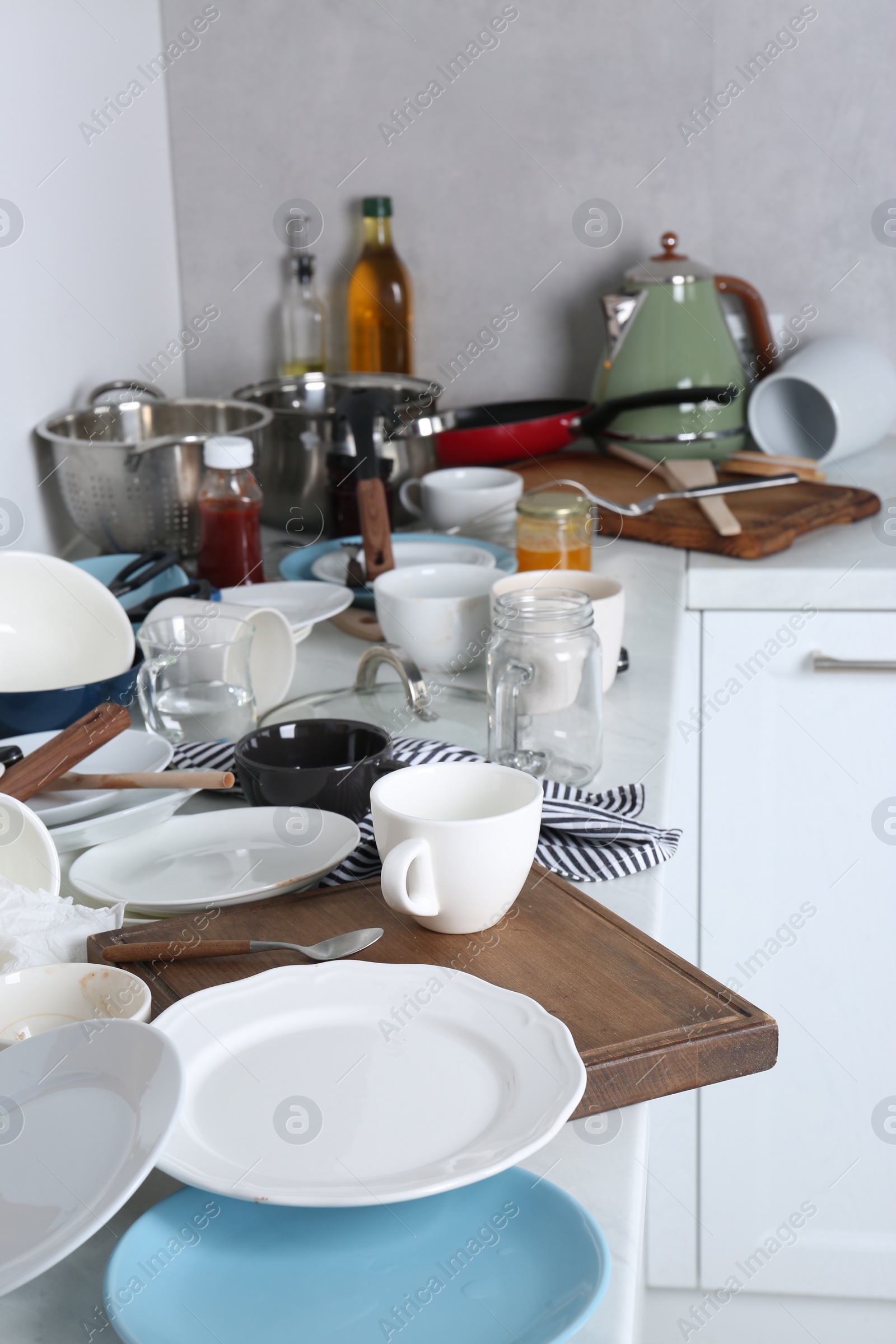 Photo of Many dirty utensils and dishware on countertop in messy kitchen