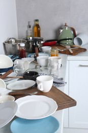 Many dirty utensils and dishware on countertop in messy kitchen