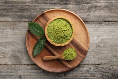 Green matcha powder and leaves on wooden table, top view