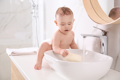 Photo of Cute little baby playing in bathroom at home