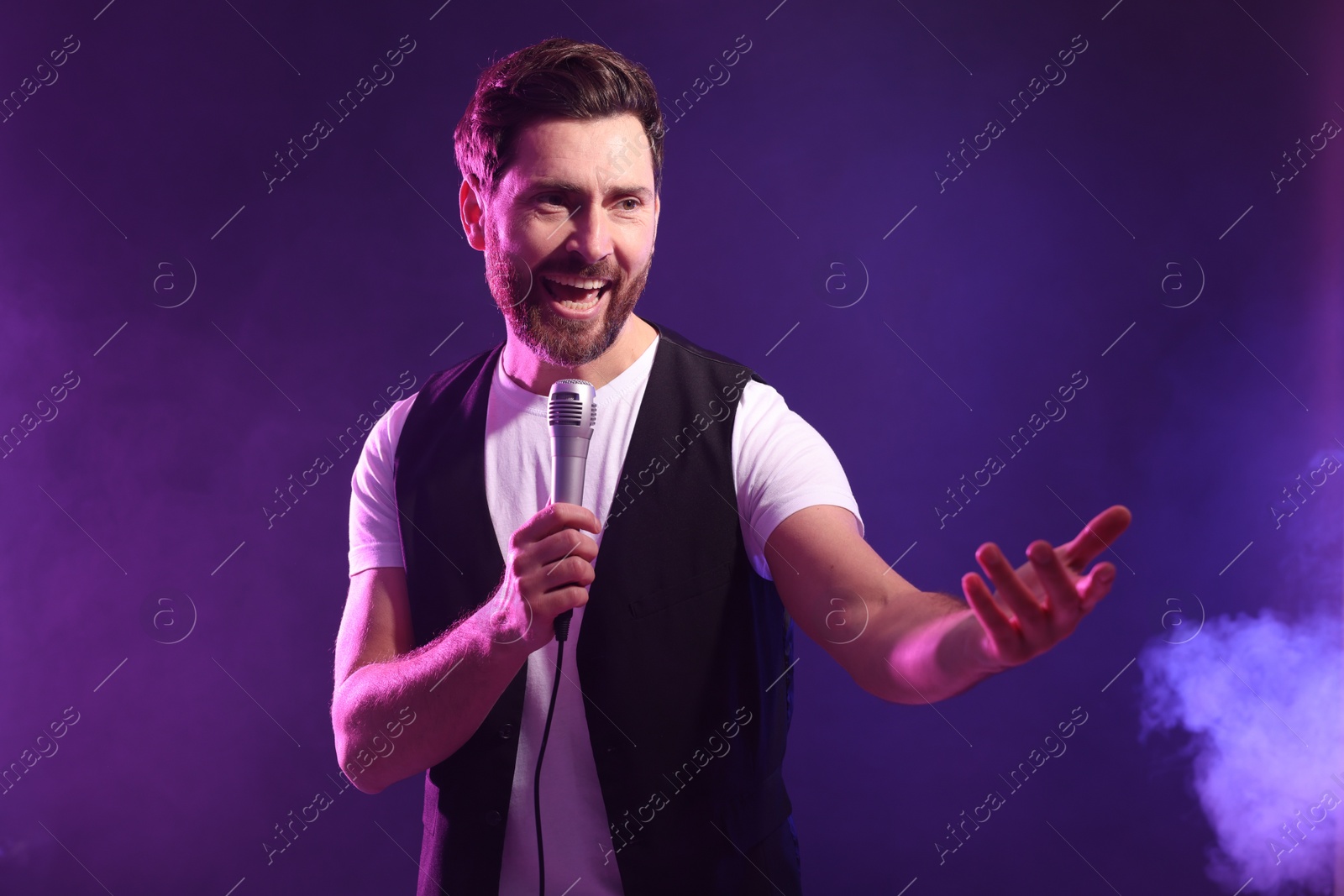 Photo of Handsome man with microphone singing in neon lights